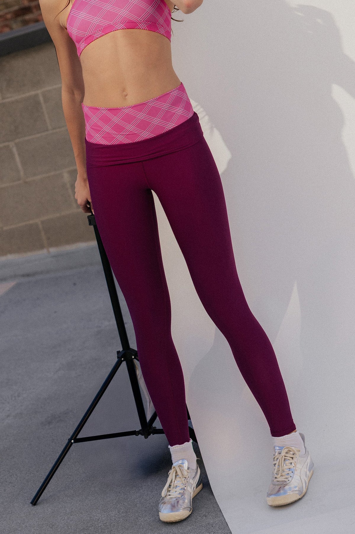 kids, A girl modeling a two-piece activewear set consisting of a pink and purple plaid halter crop top and matching high-waisted leggings in a studio setting.