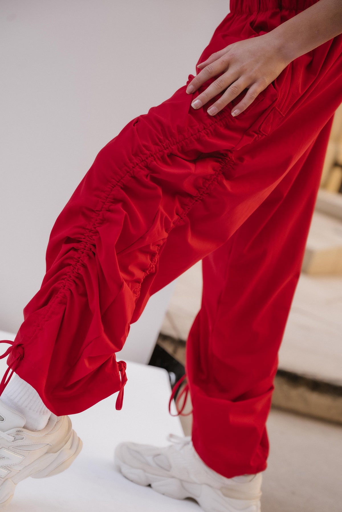kids, A close-up of a person wearing bright red ruched drawstring pants with white sneakers in an indoor setting.