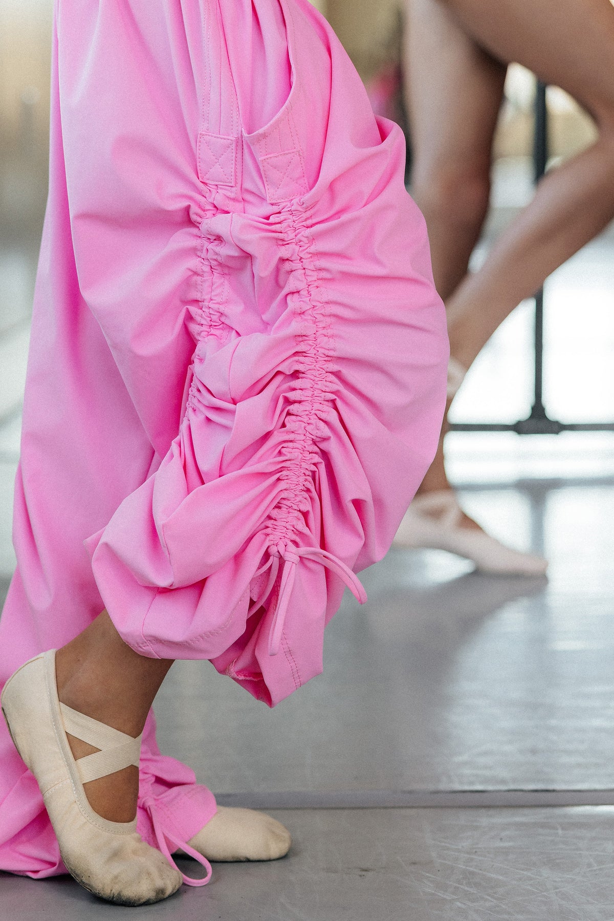 kids, A person wearing bright pink drawstring pants with gathered side details and elastic cuffs, paired with pink ballet  shoes in a dance studio.