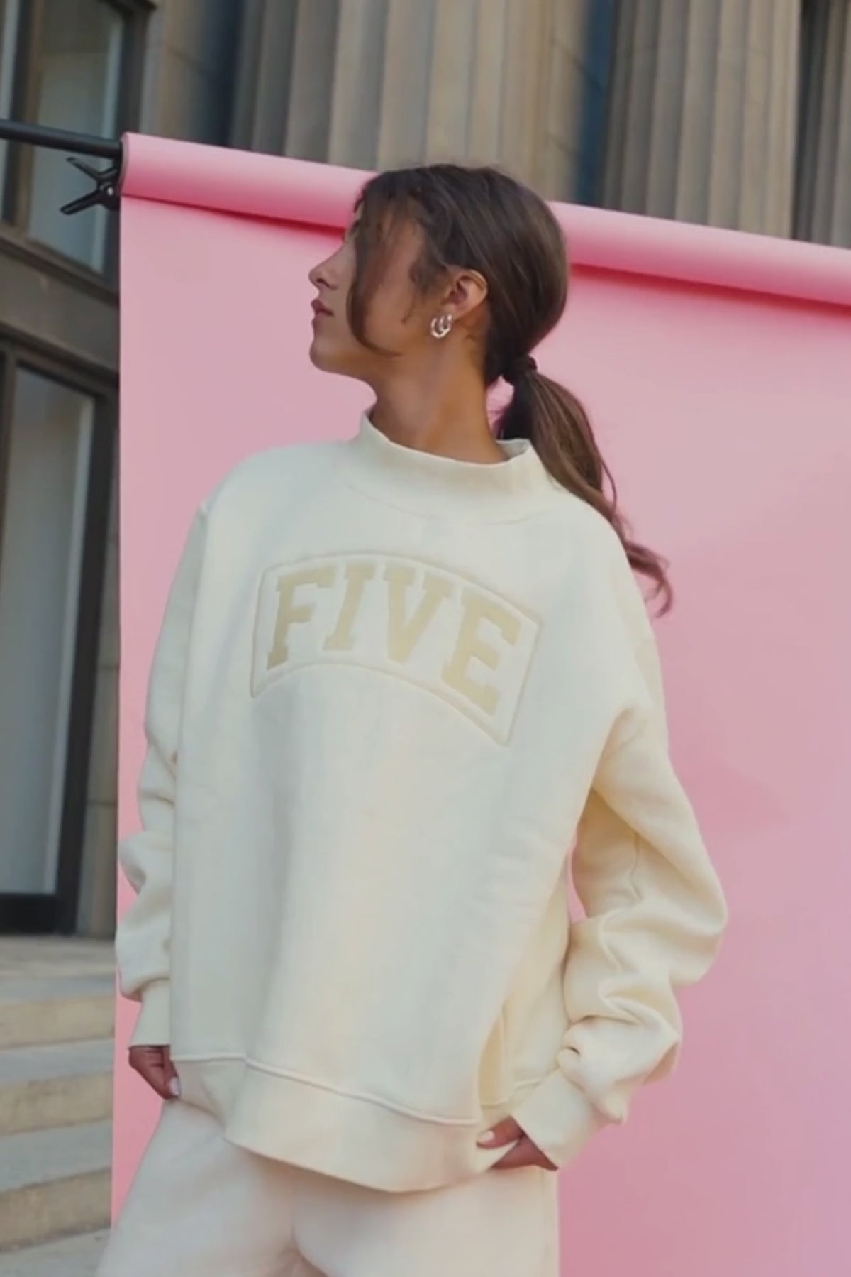 kids, A girl wearing a butter-yellow colored sweatshirt with 'FIVE' arched in a lighter beige color across the chest, standing on stone steps.