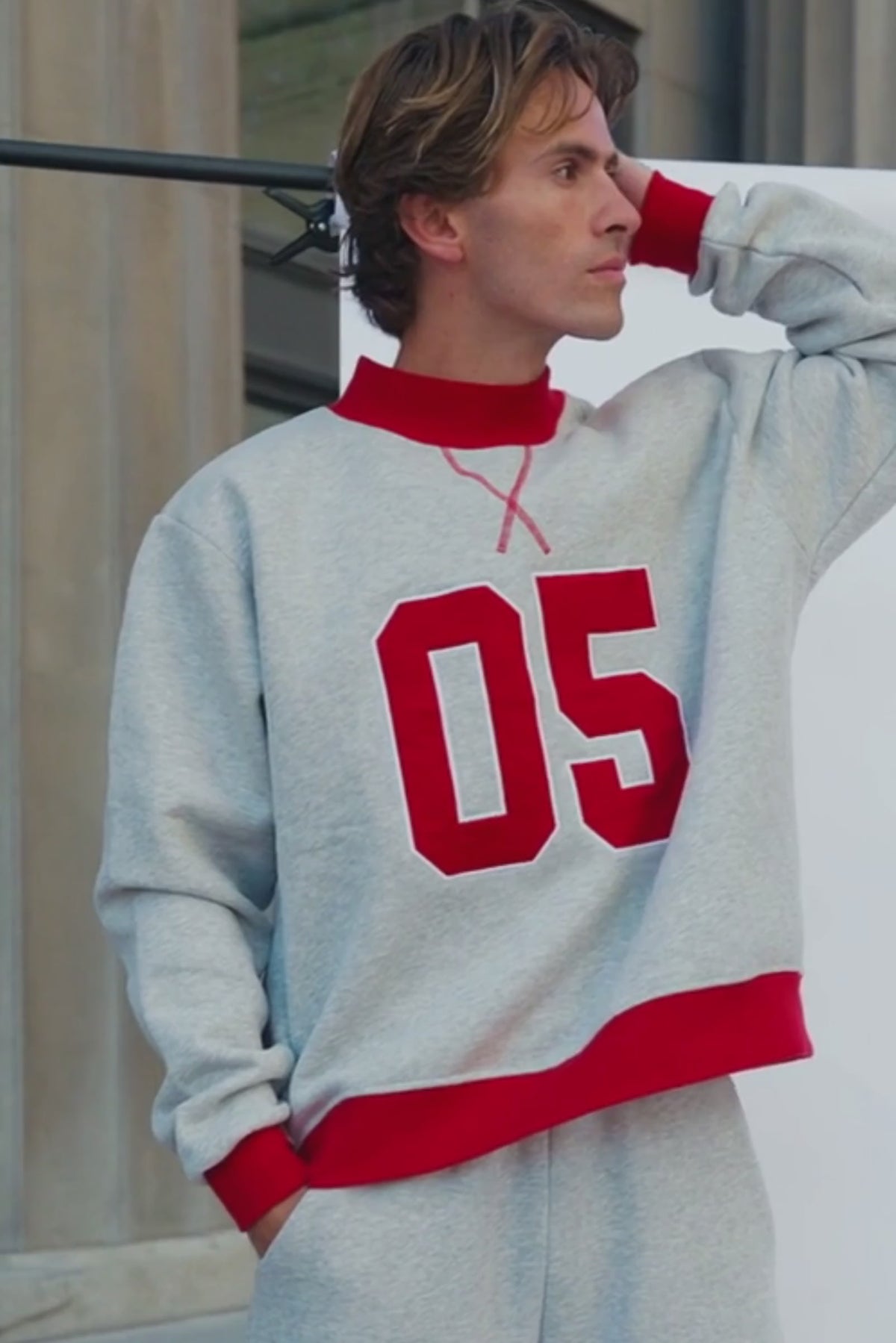 mens, A man wearing a light gray heather crewneck sweatshirt with bold red ribbed trim and large red '05' lettering on the front, paired with matching gray sweatpants.